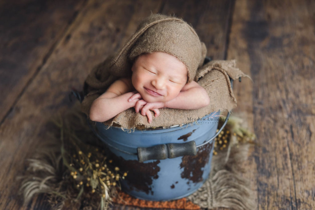 Newborn photography baby smiling in vintage rusty bucket