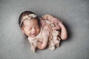 Newborn girl posing and smiling on grey background