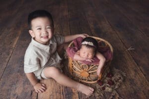 Newborn photoshoot sibling shot with elder brother smiling at the camera