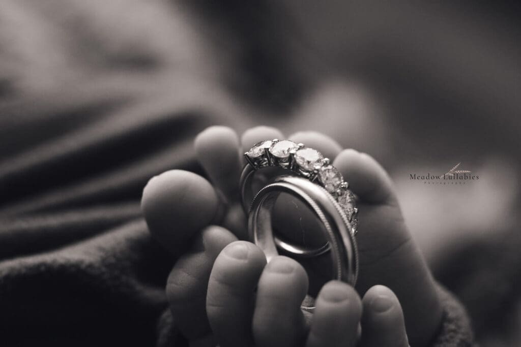 Closeup shot of parents wedding rings in newborn baby's feet