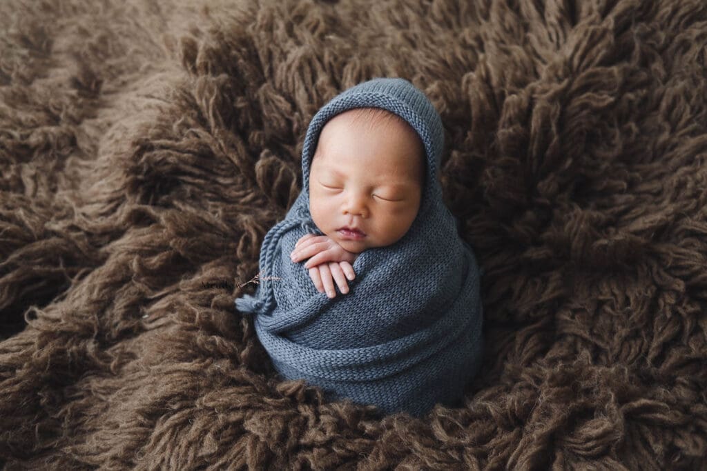Newborn photography baby blue wrap in potato sack pose