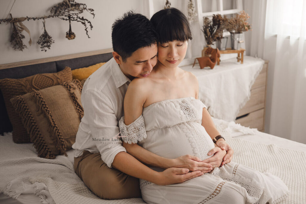 Maternity photoshoot couple in the moment posing on bed