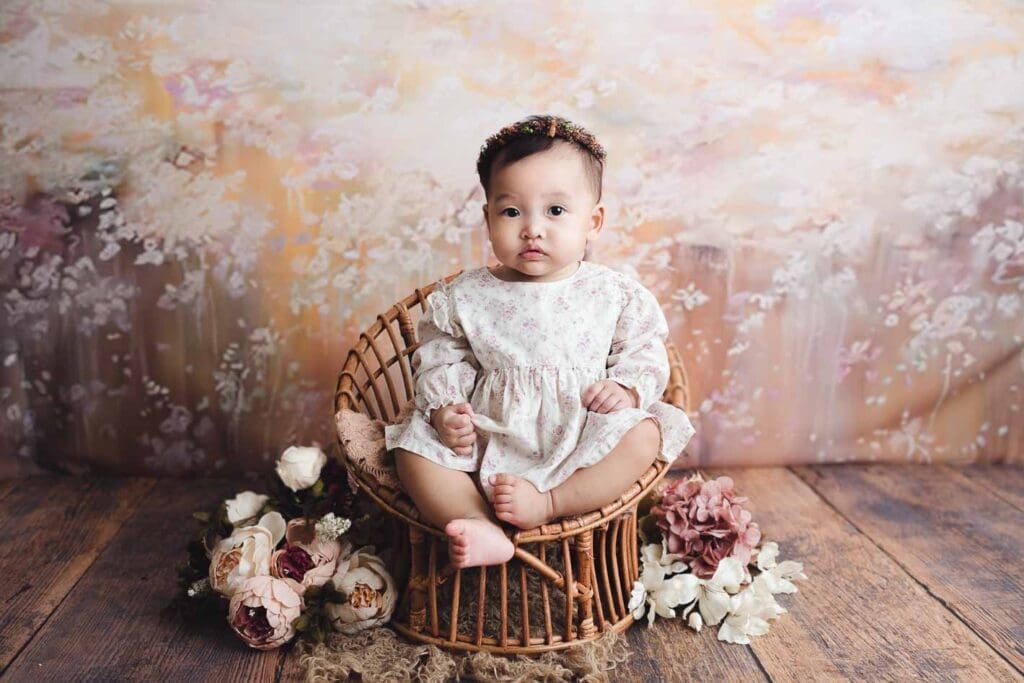 Baby on a vintage rattan stool with floral backdrop