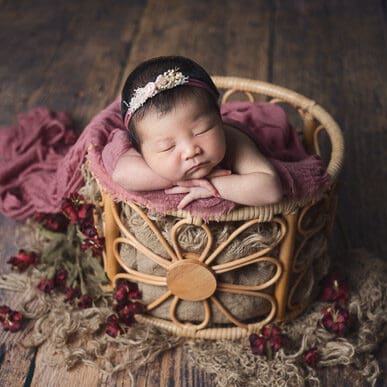 Newborn photography baby sleeping in flower petal basket prop