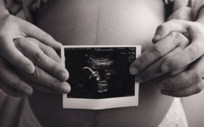 Maternity photoshoot - couple holding ultrasound film in front of tummy