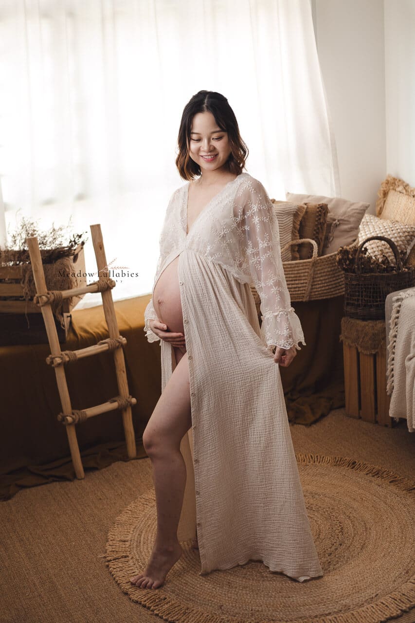 Young mother-to-be posing for her maternity photoshoot wearing a boho influence maternity dress in rustic decor