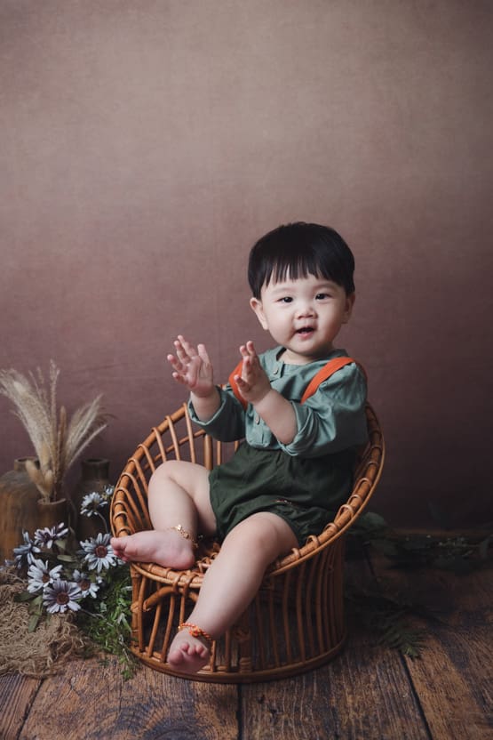 Milestone Baby Photoshoot Baby photoshoot: 10 months old baby clapping hands sitting on vintage rattan chair